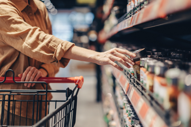 Kobieta robiąca zakupy w markecie i zdejmująca produkty z półki Kobieta robiąca zakupy w markecie i zdejmująca produkty z półki